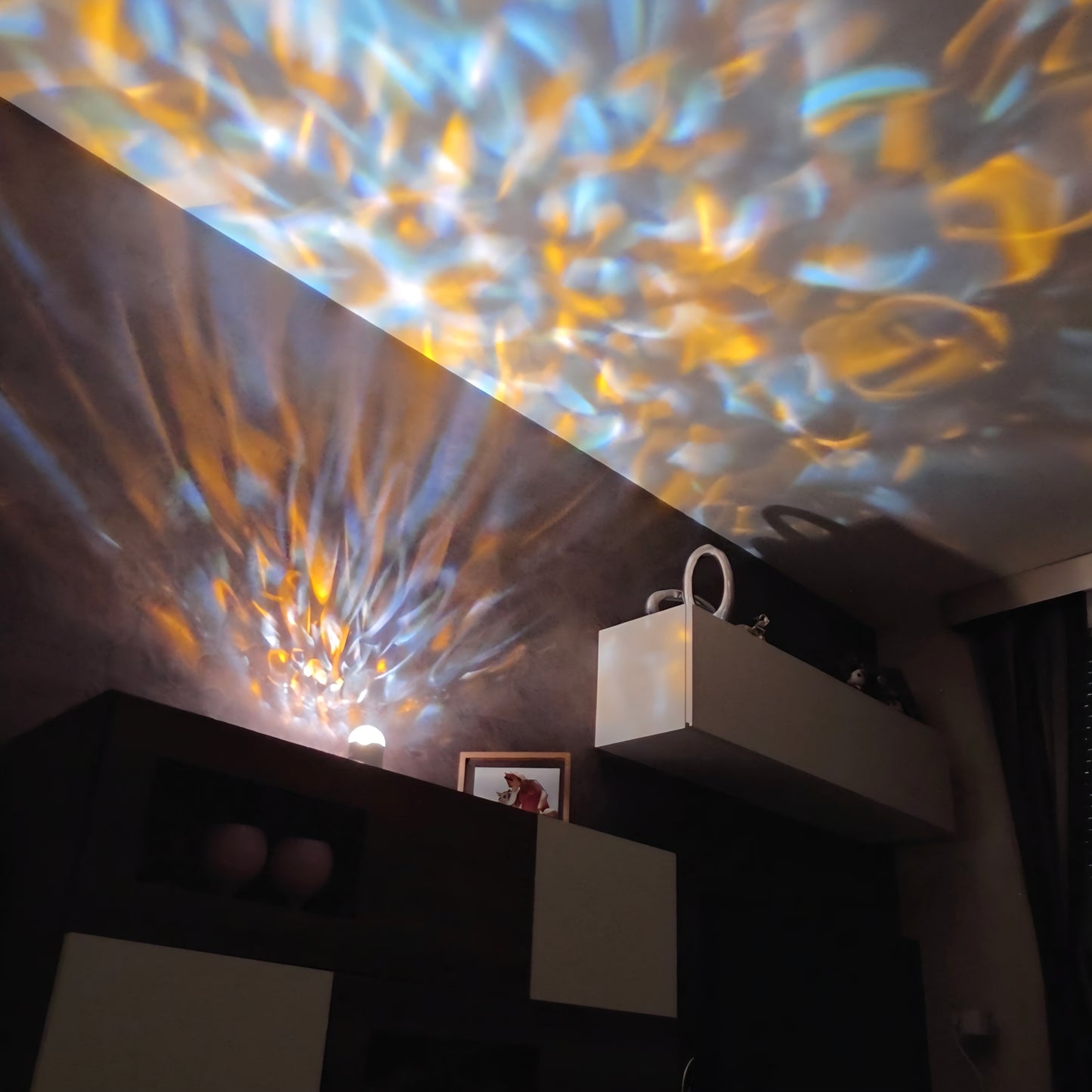 Ambient blue and gold water ripple reflections illuminating a modern room ceiling and walls.